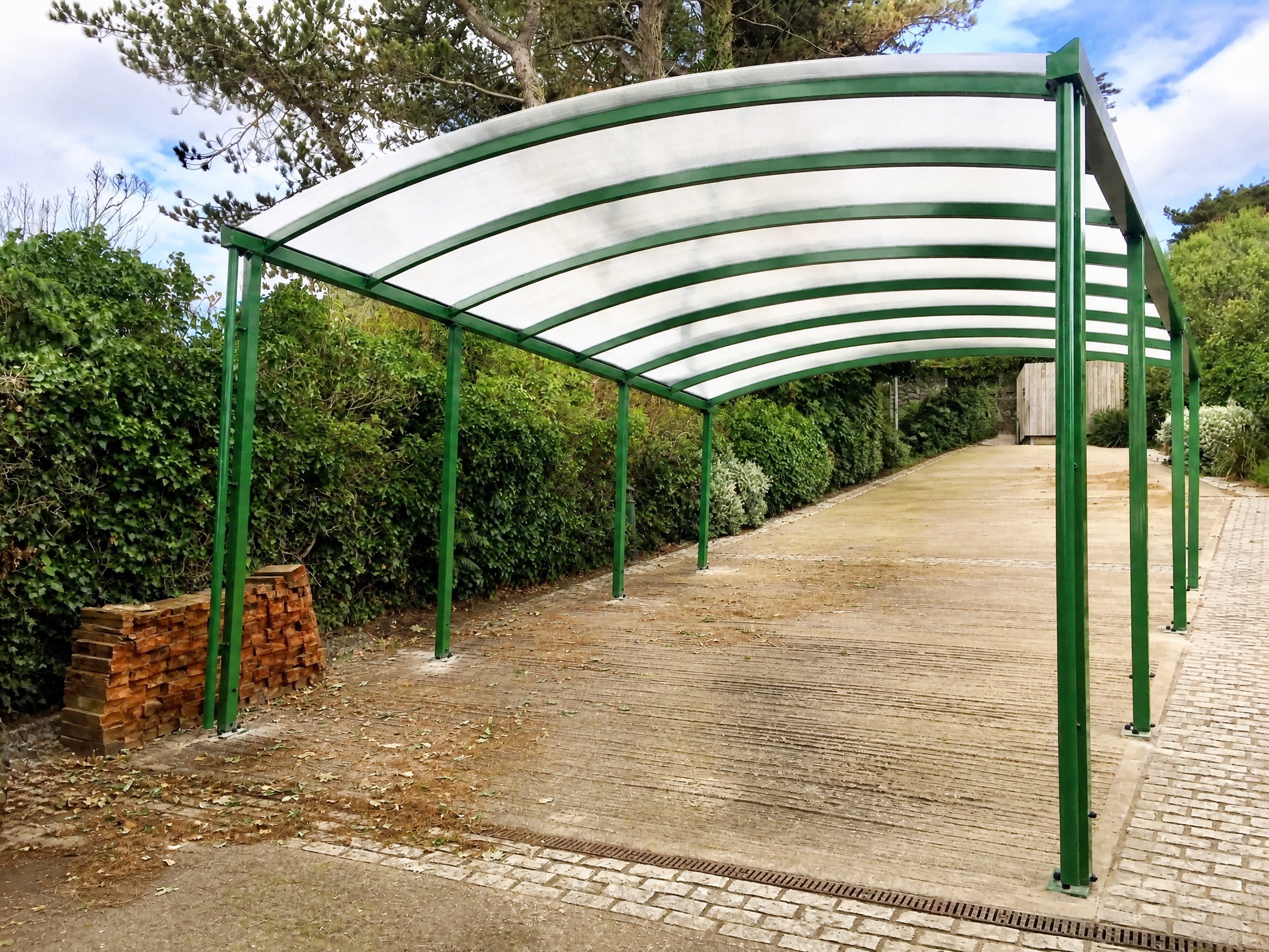 Large green-framed arched shelter covering a long driveway