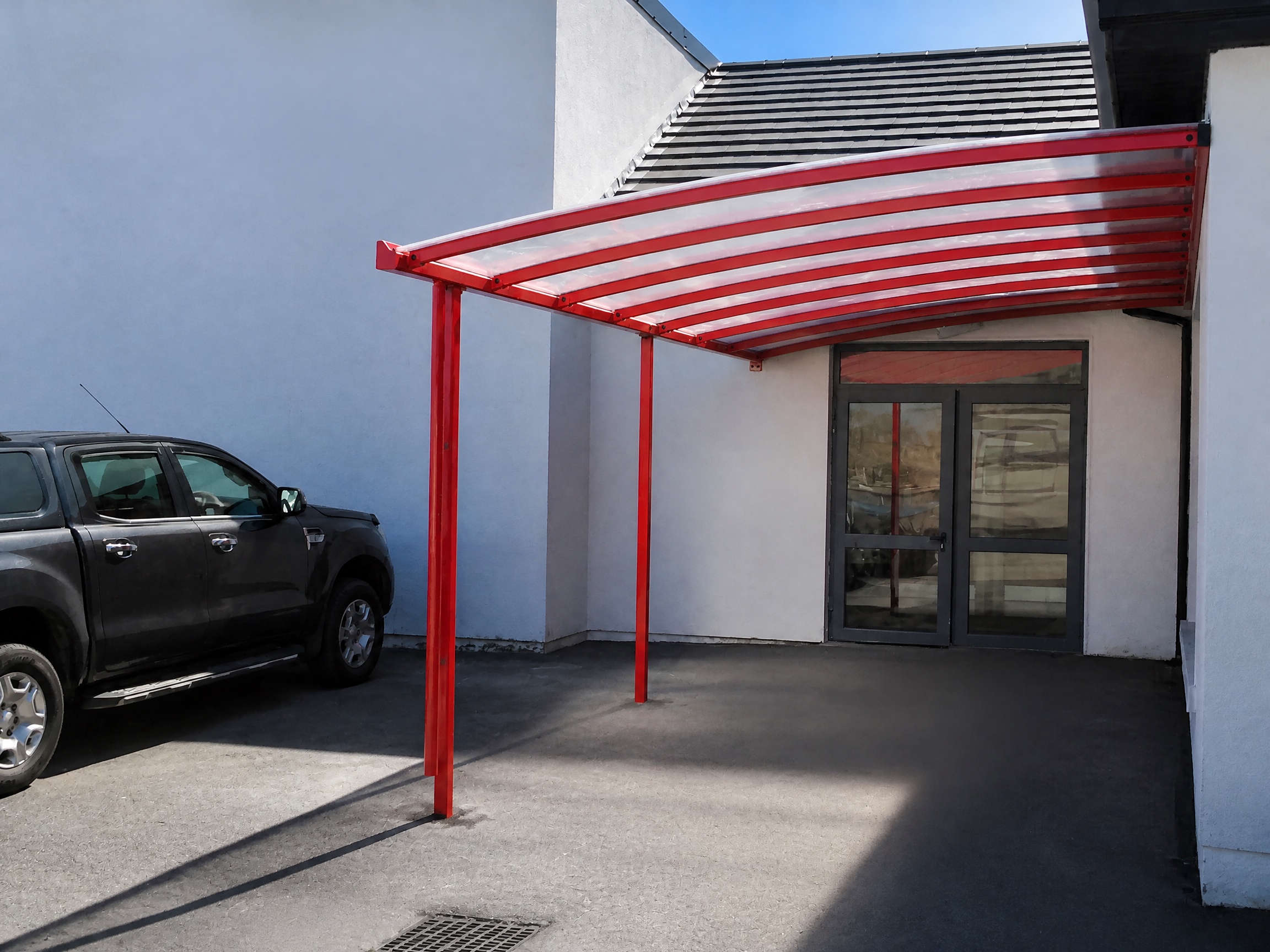 Red steel canopy installed beside a building
